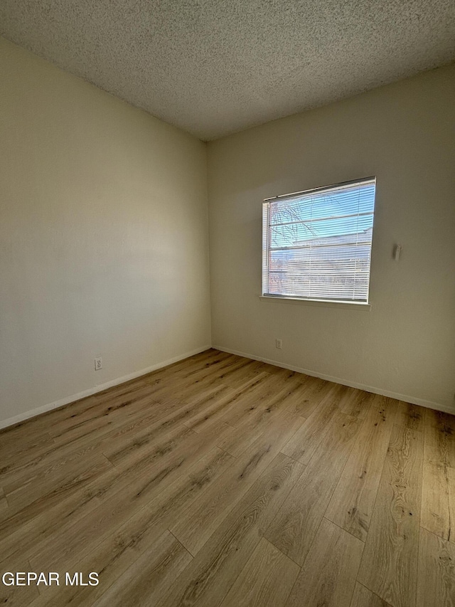 empty room featuring light hardwood / wood-style floors and a textured ceiling