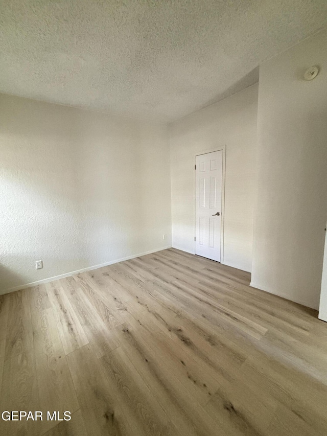 unfurnished room featuring light wood-type flooring and a textured ceiling