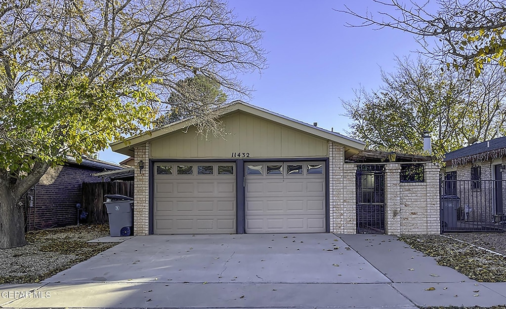 garage featuring concrete driveway and fence