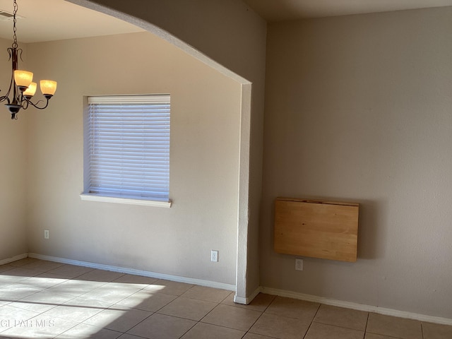 tiled empty room featuring an inviting chandelier