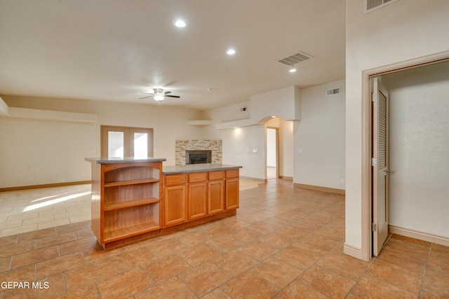 kitchen with ceiling fan and a stone fireplace