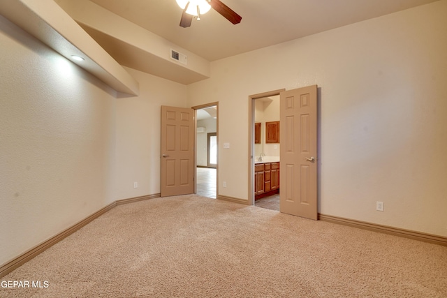 unfurnished bedroom featuring ensuite bathroom, ceiling fan, and light colored carpet