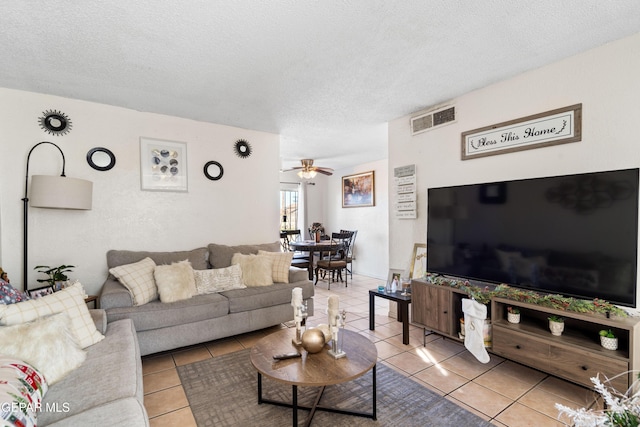 living room with ceiling fan, light tile patterned flooring, and a textured ceiling