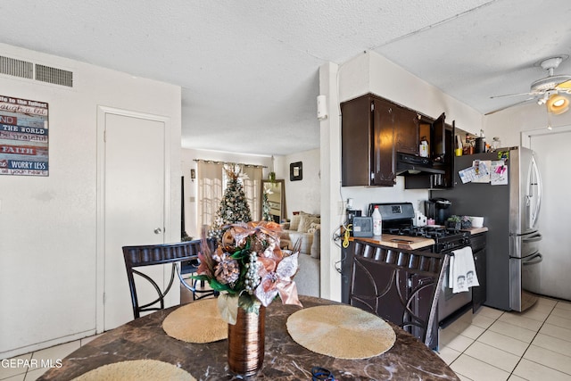 dining area featuring ceiling fan, light tile patterned flooring, and a textured ceiling