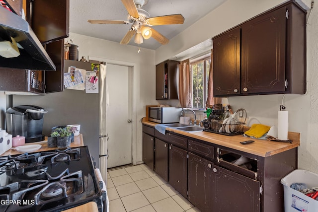 kitchen with black range with gas stovetop, sink, light tile patterned floors, dark brown cabinetry, and extractor fan