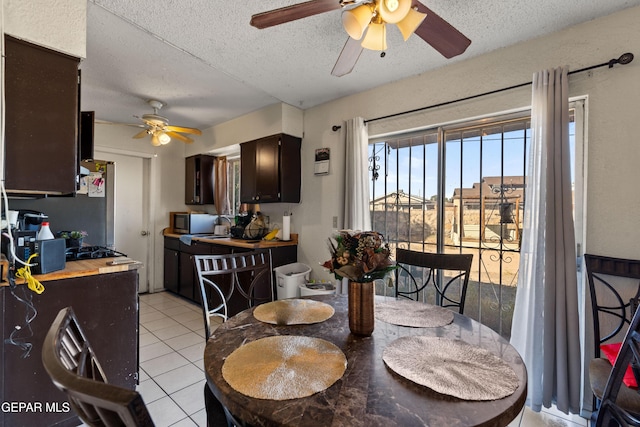 tiled dining space featuring ceiling fan and a textured ceiling