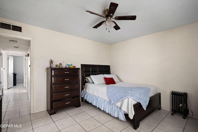 tiled bedroom with radiator heating unit, a textured ceiling, and ceiling fan