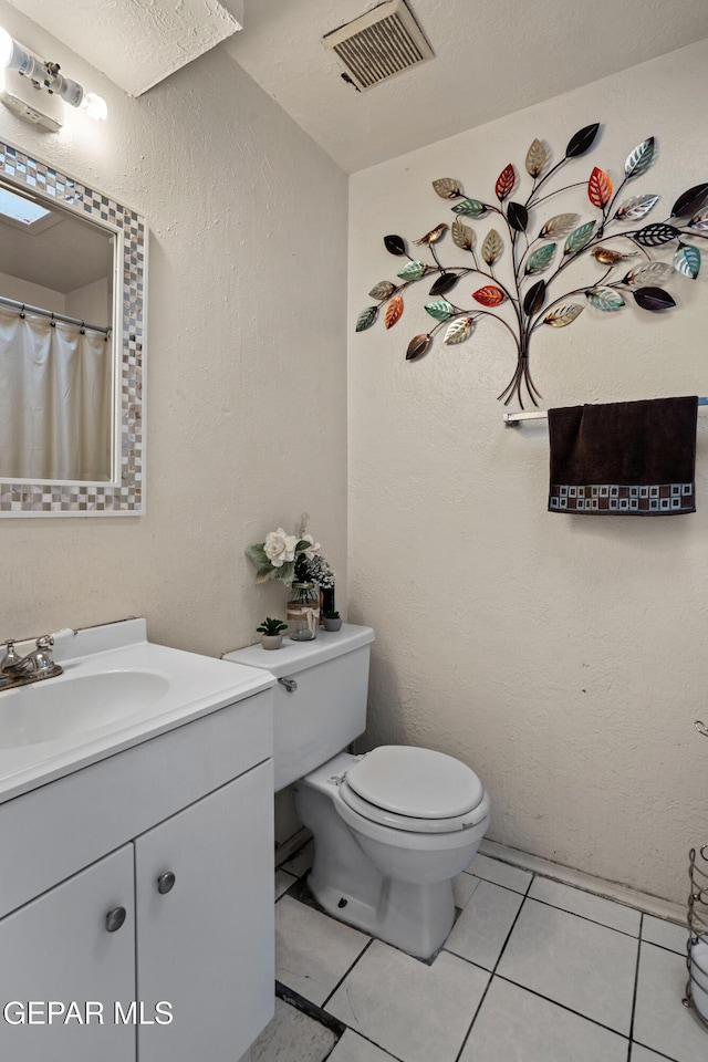 bathroom with tile patterned floors, vanity, a textured ceiling, and toilet