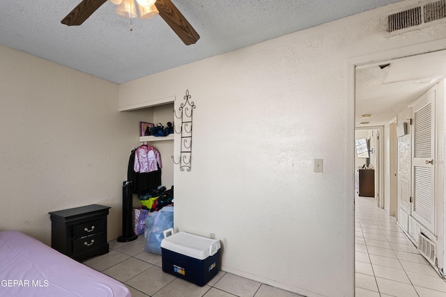 tiled bedroom with ceiling fan and a textured ceiling