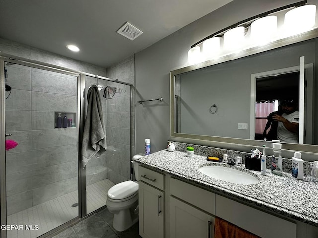 bathroom featuring tile patterned floors, vanity, a shower with shower door, and toilet