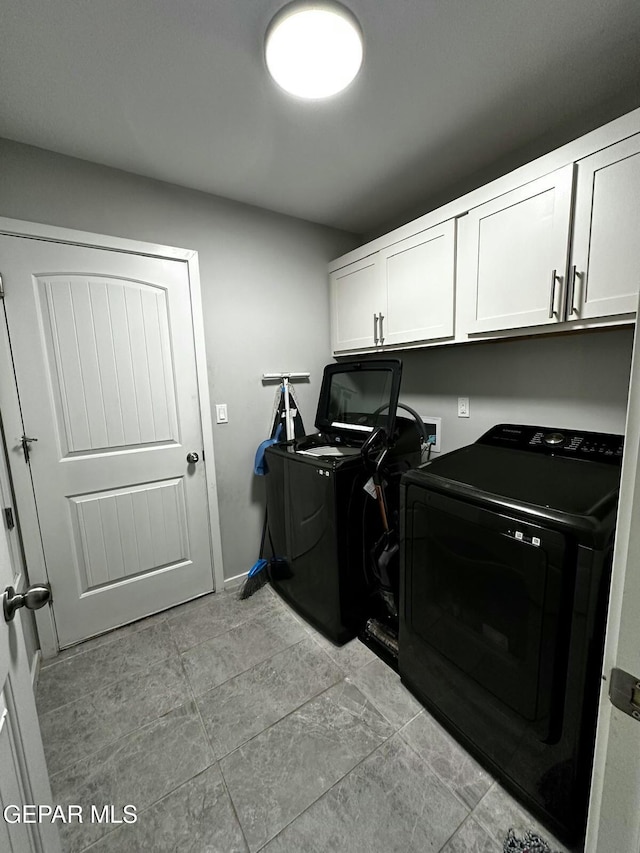 washroom featuring washing machine and clothes dryer and cabinets