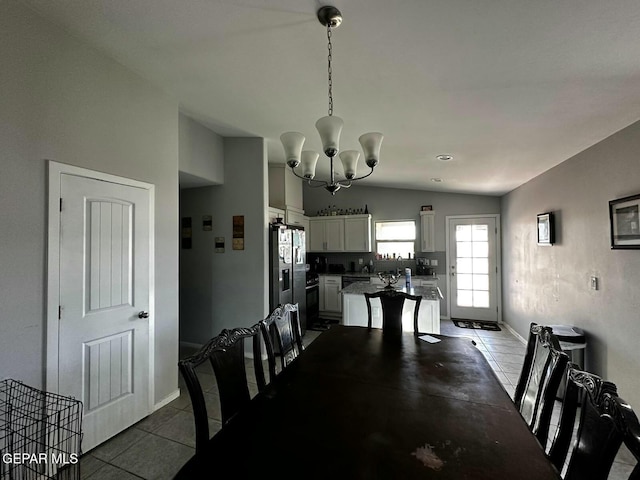 dining room with tile patterned flooring, an inviting chandelier, and lofted ceiling