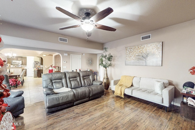 living room with wood-type flooring and ceiling fan with notable chandelier