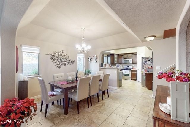 dining space featuring light tile patterned flooring, a textured ceiling, and a notable chandelier