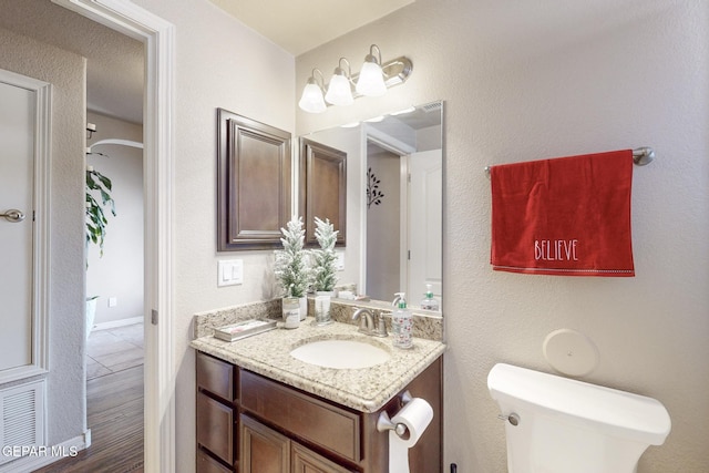 bathroom with hardwood / wood-style floors, vanity, and toilet