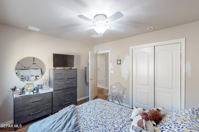 bedroom with ceiling fan, dark hardwood / wood-style flooring, a textured ceiling, and a closet