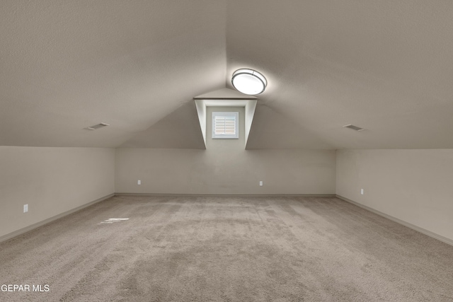 bonus room featuring a textured ceiling, light colored carpet, and vaulted ceiling