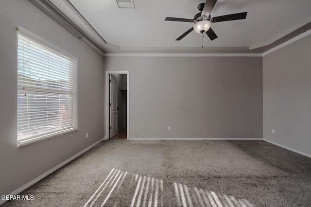 carpeted empty room featuring a raised ceiling, crown molding, and ceiling fan