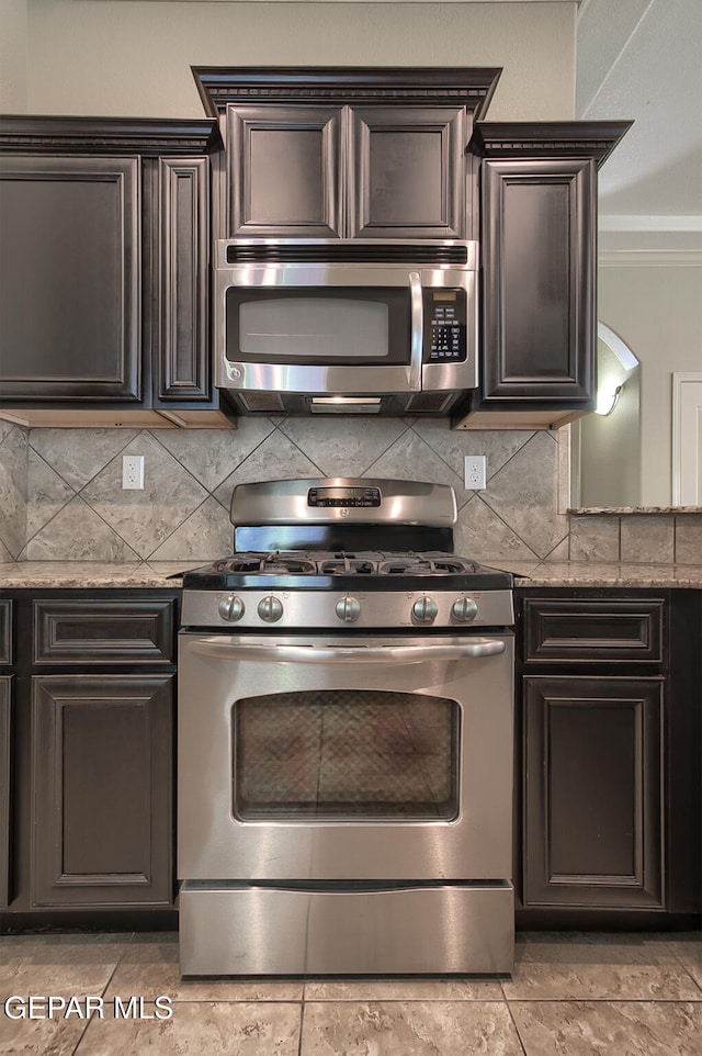 kitchen with backsplash, light stone counters, ornamental molding, and appliances with stainless steel finishes