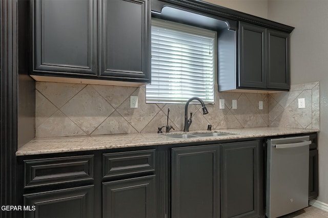 kitchen featuring dishwasher, backsplash, light stone counters, and sink