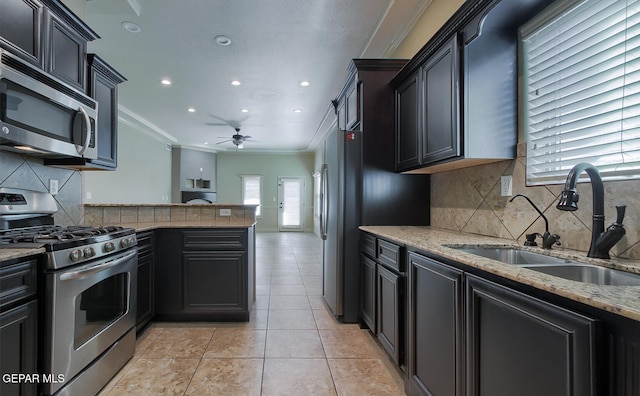 kitchen featuring backsplash, stainless steel appliances, ceiling fan, crown molding, and sink