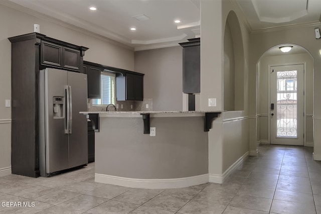 kitchen with a kitchen breakfast bar, plenty of natural light, stainless steel fridge with ice dispenser, and kitchen peninsula