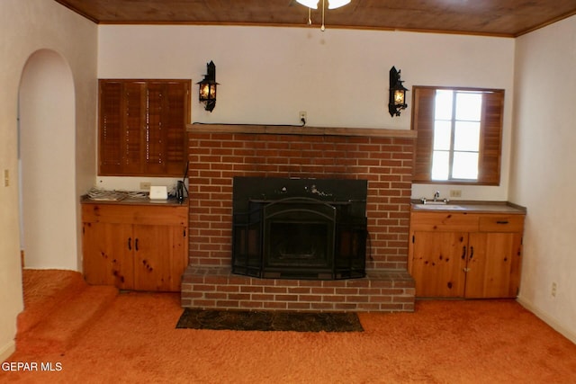 unfurnished living room featuring light carpet, ornamental molding, a brick fireplace, and wooden ceiling