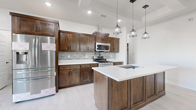 kitchen with appliances with stainless steel finishes, backsplash, dark brown cabinetry, a raised ceiling, and hanging light fixtures