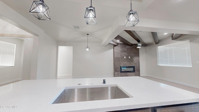 kitchen featuring beam ceiling, sink, hanging light fixtures, and a premium fireplace