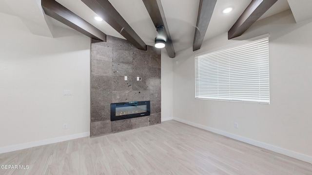 unfurnished living room featuring beamed ceiling, light hardwood / wood-style floors, and a tiled fireplace