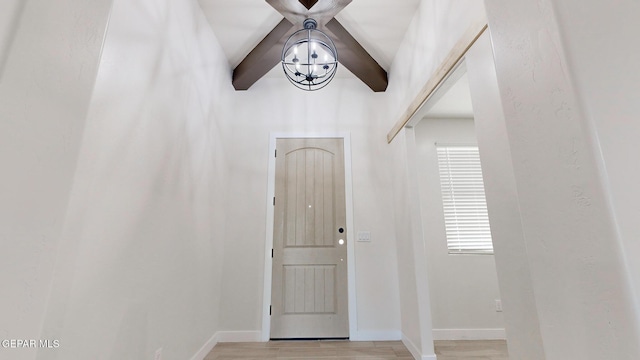 foyer entrance featuring lofted ceiling with beams and light wood-type flooring