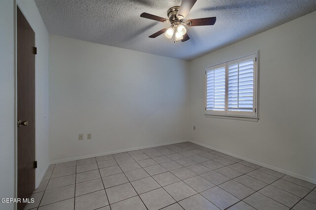 spare room featuring ceiling fan, light tile patterned flooring, and a textured ceiling