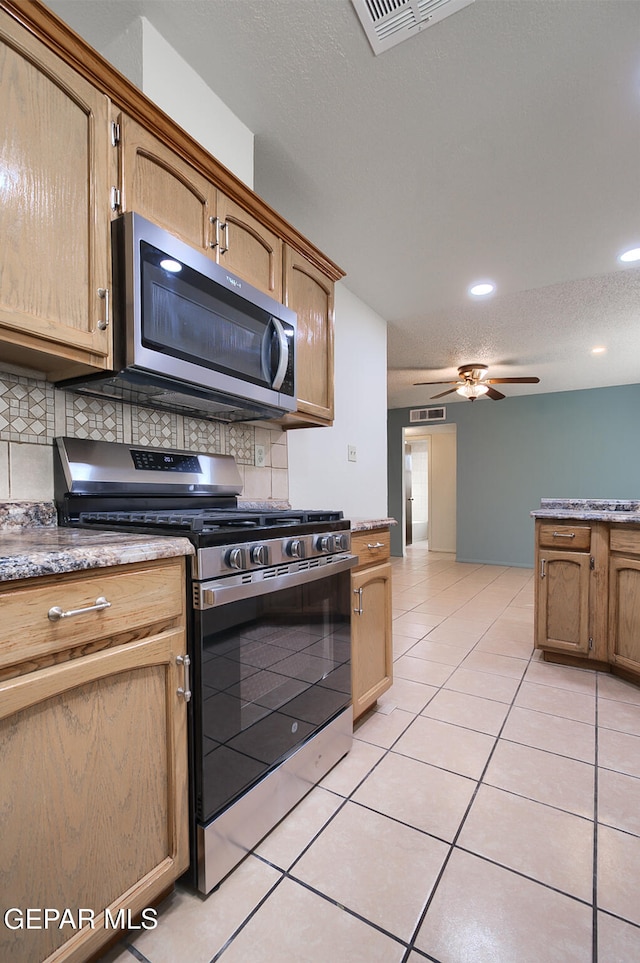 kitchen with backsplash, a textured ceiling, stainless steel appliances, ceiling fan, and light tile patterned flooring