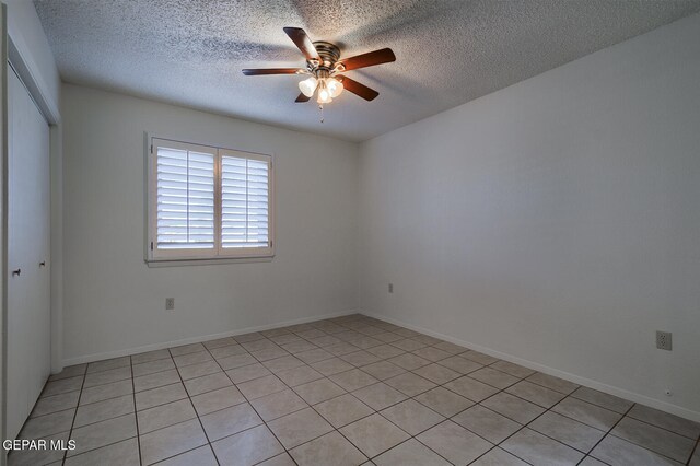 unfurnished room with ceiling fan, light tile patterned floors, and a textured ceiling