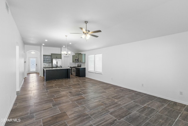 unfurnished living room with ceiling fan with notable chandelier and vaulted ceiling