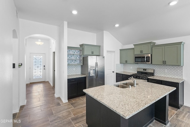 kitchen featuring appliances with stainless steel finishes, a center island with sink, light stone counters, and sink