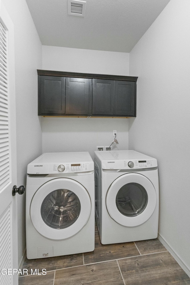 clothes washing area featuring cabinets and independent washer and dryer