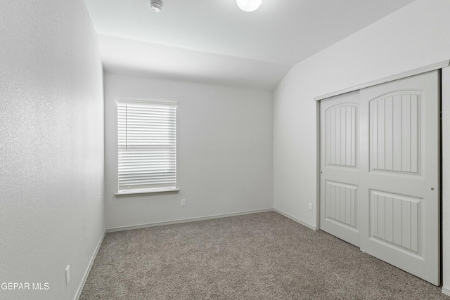 unfurnished bedroom featuring light colored carpet, a closet, and lofted ceiling