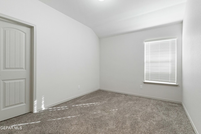 carpeted empty room featuring vaulted ceiling