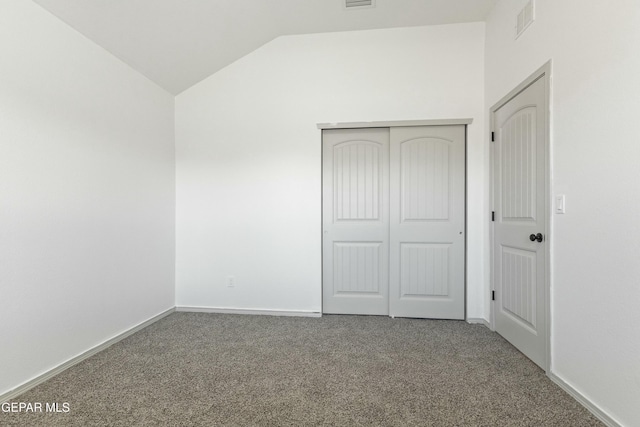 unfurnished bedroom featuring carpet floors, vaulted ceiling, and a closet