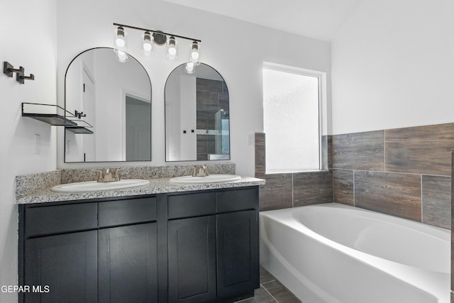 bathroom with a washtub, vanity, and tile patterned floors