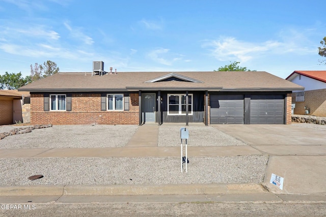 single story home with central AC unit and a garage