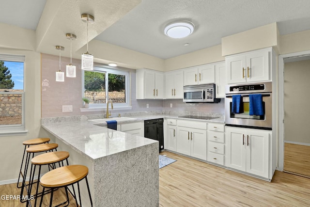 kitchen with kitchen peninsula, sink, black appliances, pendant lighting, and white cabinets