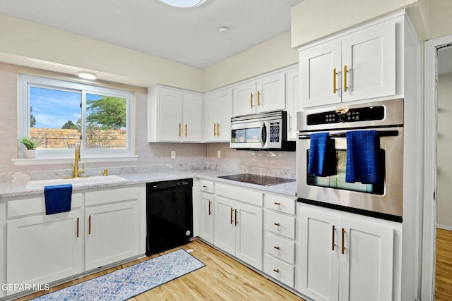 kitchen featuring sink, white cabinetry, light hardwood / wood-style flooring, and black appliances