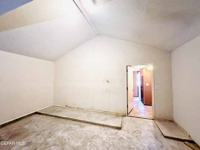 empty room featuring a textured ceiling and lofted ceiling