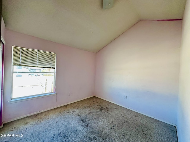 carpeted empty room with lofted ceiling