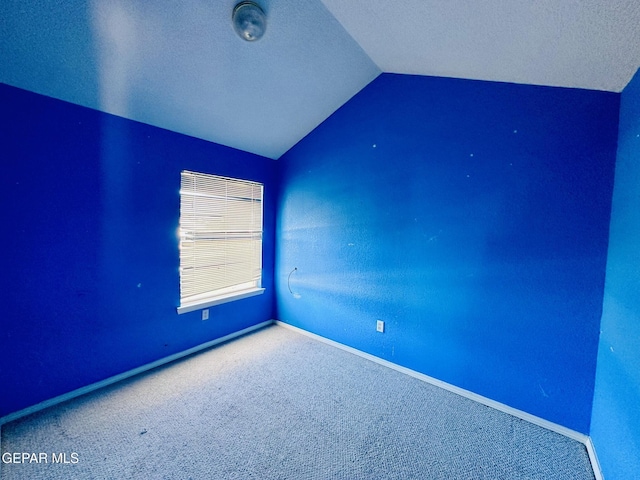 carpeted empty room with a textured ceiling and lofted ceiling