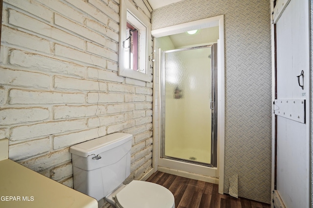 bathroom with wood-type flooring, toilet, an enclosed shower, and brick wall