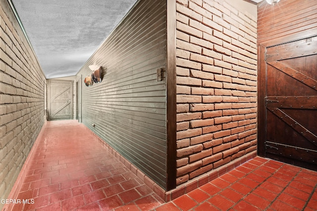 interior space with a textured ceiling and brick wall