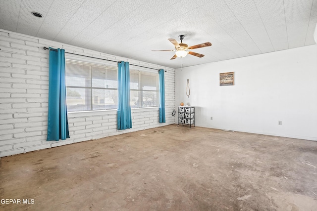 empty room with concrete flooring, ceiling fan, and brick wall